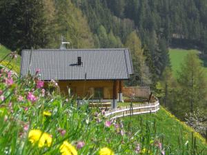 una casa en una colina con una valla y flores en Chalet Niederhaushof, en Ultimo