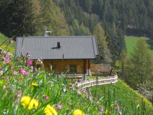 a house on a hill with a fence and flowers at Chalet Niederhaushof in Ultimo