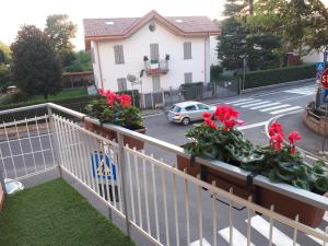 a white fence with red flowers on a street at casa leonardo in Azzano San Paolo