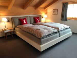 a bedroom with a large bed with red pillows at Penthouse Apartment - Sez Ner in Obersaxen