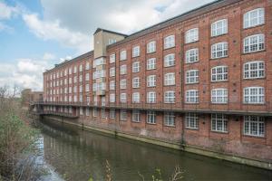 a large brick building next to a river at ChocoLets - The Foss Suite in York