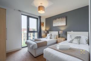 a bedroom with two beds and a large window at Arcadian City Centre Apartment in Birmingham