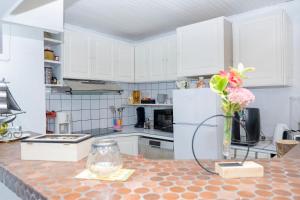 a kitchen with white cabinets and a vase of flowers on a counter at Une HALTE Quelque PART in Cheminot