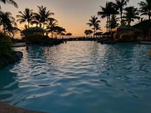 a pool at a resort at sunset with palm trees at Maui Westside: Honua kai Konea 312/314 in Kaanapali