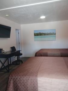 a hotel room with two beds and a desk and a television at Modoc Inn in Alturas