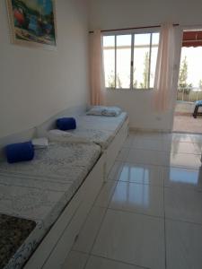 Dieses weiße Zimmer verfügt über 2 Betten und ein Fenster. in der Unterkunft Aquamarine House in Itanhaém