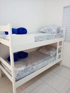 ein weißes Etagenbett mit blauer und weißer Bettwäsche und Kissen in der Unterkunft Aquamarine House in Itanhaém