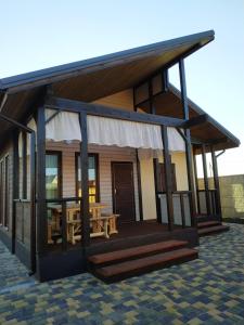 a house with a deck with a picnic table at Дом Дискавери семейный у моря! in Chornomorsk