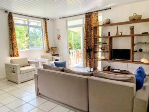 een woonkamer met 2 banken en een tv bij TAHITI - Fare Mitinui Surf Break in Mahina