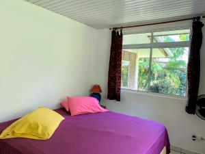 a bedroom with a purple bed and a window at TAHITI - Fare Mitinui Surf Break in Mahina