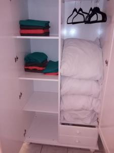 um armário branco com uma almofada e toalhas dobráveis em Studio Climatisé Côte-sous-le-vent em Baillif