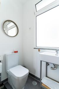 La salle de bains est pourvue de toilettes blanches et d'un miroir. dans l'établissement Madeira Surf Camp, à Porto da Cruz