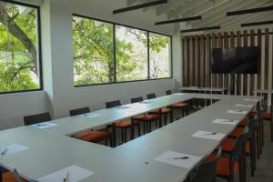une salle de conférence avec des tables, des chaises et des fenêtres dans l'établissement Hotel Y Parque Acuático La Caldera, à Villa Abasolo