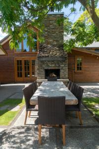 - une table et des chaises avec une cheminée en face d'une maison dans l'établissement Wanaka Homestead Lodge & Cottages, à Wanaka