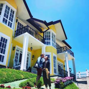 two people standing in front of a yellow house at Luxe Wilderness in Nuwara Eliya