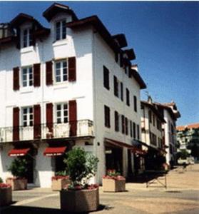 Un grand bâtiment blanc avec balcon se trouve dans une rue. dans l'établissement Villa Erdian, à Saint-Jean-de-Luz