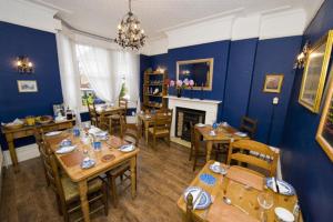 a dining room with blue walls and wooden tables and chairs at The Beckett Guest House in York