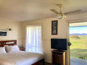 a bedroom with a bed and a flat screen tv at Promhills Cabins in Yanakie