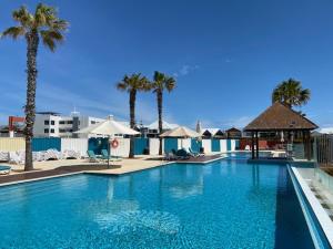 a large blue swimming pool with palm trees and umbrellas at Dolphin View 404 in Mandurah