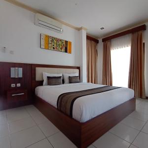 a bedroom with a large bed and a window at Friends Beach Hotel in Kuta Lombok