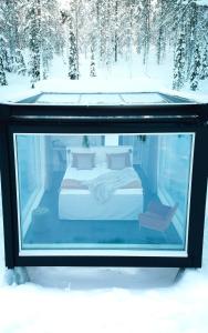 a bed in a glass aquarium in the snow at Arctic Skylight Lodge in Äkäslompolo