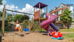 Eine Frau, die auf einer Rutsche auf einem Spielplatz sitzt. in der Unterkunft Adrasan Klados Hotel in Adrasan