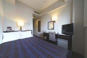 a hotel room with a bed and a flat screen tv at Meitetsu Inn Nagoya Nishiki in Nagoya