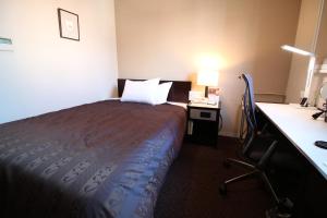 a hotel room with a bed and a desk with a lamp at Meitetsu Inn Nagoya Nishiki in Nagoya