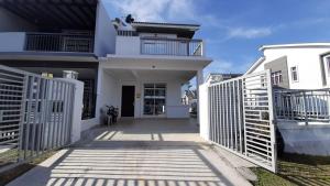 a white house with a gate in front of it at Homestay Greenway in Pasir Gudang