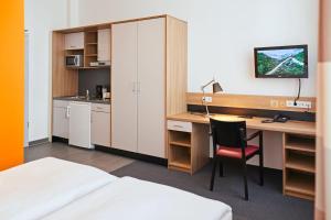 ein Hotelzimmer mit einem Schreibtisch, einem Bett und einem Computer in der Unterkunft Townhouse Düsseldorf in Düsseldorf