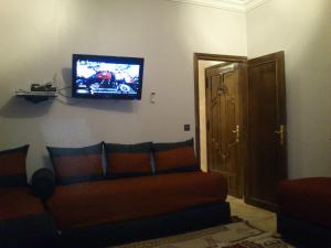 un soggiorno con divano e TV a parete di Magnifique Appartement Plage Saidia a Saïdia