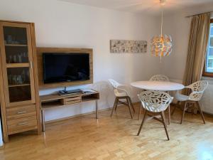 un soggiorno con tavolo, sedie e TV di Apartment Anita a Ellmau