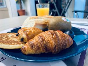 un piatto blu con prodotti da forno, pane e un bicchiere di succo d'arancia di Hotel Inn Design Dijon Sud a Marsannay-la-Côte