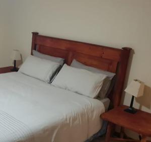 a bedroom with a bed with a wooden headboard and two tables at Log Cabin Ramsgate in Margate