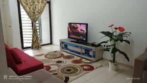 a living room with a flat screen tv on a table at Pok Su Homestay Balok in Kuantan +14 photos