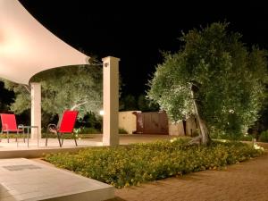 dos sillas rojas y un árbol en un jardín por la noche en Tra gli ulivi, en Putignano