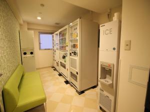 a room with refrigerators and a green chair in it at Meitetsu Inn Nagoya Nishiki in Nagoya