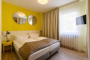 um quarto com uma cama e uma parede amarela em Hotel Glockengasse em Colônia