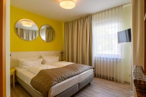 a bedroom with a bed with yellow walls and mirrors at Hotel Glockengasse in Cologne