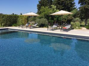 a swimming pool with chairs and umbrellas at Le Mas Terre des Anges in Sarrians