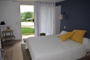 Un dormitorio con una cama con almohadas amarillas y una ventana en Domaine du BOURNAT, en Camboulit