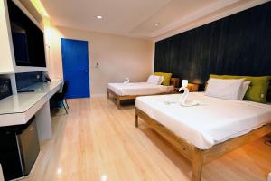 a hotel room with two beds and a television at Pescadores Suites Moalboal in Moalboal