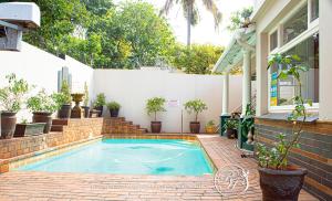 a swimming pool in front of a house with potted plants at Roseland House in Durban
