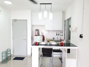 a kitchen with white cabinets and a counter with stools at Apartment Servis UITM Puncak Alam in Bandar Puncak Alam