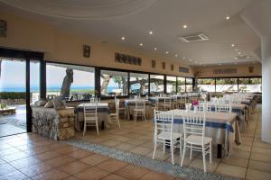restauracja ze stołami i krzesłami oraz oceanem w obiekcie Torre San Vito Hotel Villaggio w mieście Gaeta