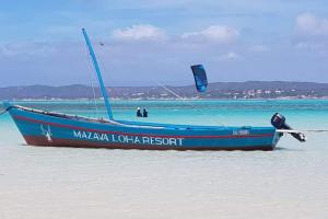 Mazava Loha Resort في دييجو سواريز: القارب الأزرق الجلسه على الرمال على الشاطئ
