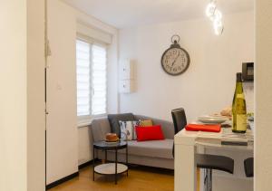 a living room with a couch and a clock on the wall at Grünewald Colmar - Studio 2 pers - Parking in Colmar