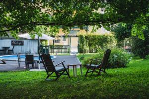 three chairs sitting in the grass under a tree at Riedz Apartments Innsbruck- Zentrales Apartmenthaus mit grüner Oase in Innsbruck