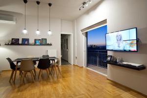 a dining room with a table and a flat screen tv at Acropolis View Penthouse N in Athens