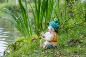 a small figurine sitting in the grass near the water at Rum Bridge Gypsy 'Rose' in Sudbury